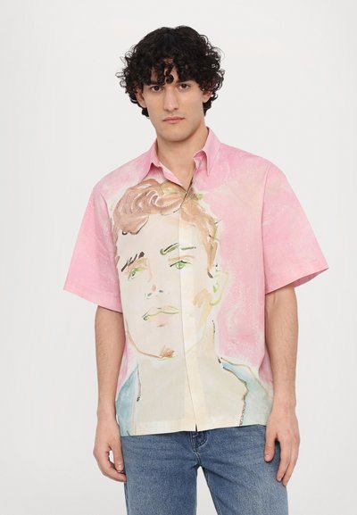 Camisa con botones de manga corta en rosa con una ilustración de cara pintada. Tejido ligero con cuello y un ajuste relajado.