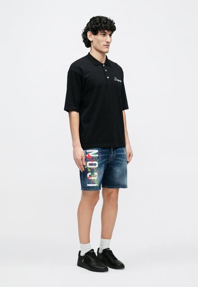 Mustast polosärgist lühikeste varrukatega ja kolme nupuga, kombineeritud siniste teksapükstega, millel on värviline plekimuster ja graafiline tekst. Mustad tennised.