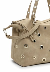 Bolso de mano de ante beige con detalles circulares en tono dorado, una cremallera superior y correas dobles. Presenta una forma holgada con detalles laterales.