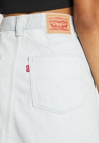 Ljusblå denimkjol med en bakficka och en beigefärgad läderetikett med röd grafisk detalj från Levi Strauss & Co.