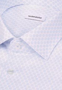 Nahaufnahme eines hellblauen Hemdes mit Muster, Knopfkragen und sichtbarem „seidensticker“-Markenetikett.