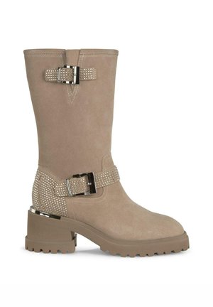 Bottine en suede tan avec un talon épais, bande embellie de clous en argent et détail de boucle en métal. Texture lisse, design à bout rond.