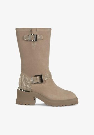 Beżowe zamszowe botki za kostkę na masywnej podeszwie, ozdobne paski z srebrnymi ćwiekami i metalowym zapięciem. Gładka tekstura, zaokrąglony nos.