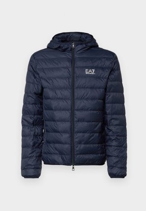 Giubbotto ecologico blu navy con cappuccio, caratterizzato da sezioni trapuntate orizzontali, zip frontale e logo EA7 sul lato sinistro del petto.