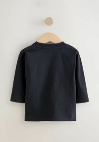 Dunkelblaues Langarmshirt aus Baumwolle, mit klassischem Rundhalsausschnitt, hängt auf einem Holzkleiderbügel vor einem hellen Hintergrund.