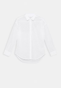 Chemise blanche à manches longues avec un design à œillets, col boutonné et ourlet arrondi. Texture lisse avec des motifs subtils.