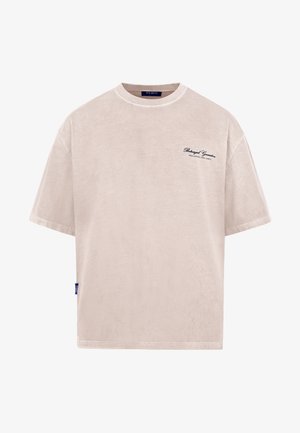 Lys beige oversized t-shirt lavet af blødt stof. Har korte ærmer og et diskret broderet logo på brystet. Enkel design.