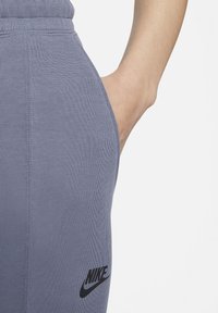 Grijze katoen joggers met een ribbelstructuur en een zijzak, met een zwart Nike-logo gedrukt op de linker bovenbeen.