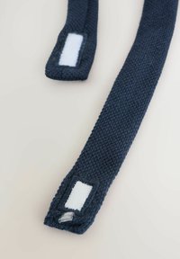 Jūras zila auduma siksnas ar teksturētu adījuma rakstu. Katram siksniņai ir balta velcro zona vienā galā drošai piepietināšanai.