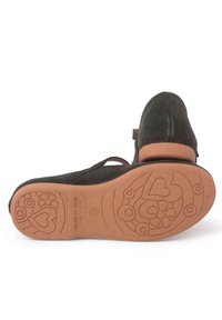 Zapato de ante negro con punta redonda, correa ajustable y suela de goma con patrones florales y de corazones.
