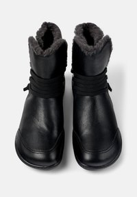 Bottines en cuir noir avec une douce doublure en fourrure grise, dotées de lacets élastiques autour de la cheville et d'un design à bout rond.