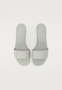 Sandales à glissière grises avec une bande texturée arborant un motif répété du logo CK. Semelle intérieure lisse et rembourrée pour le confort. Semelle en caoutchouc, design minimaliste.