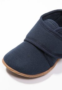 Marine stof mocassin met elastische band, getextureerde bovenkant en flexibele tan rubberen zool. Rond neusontwerp, zichtbare gestikte accenten.