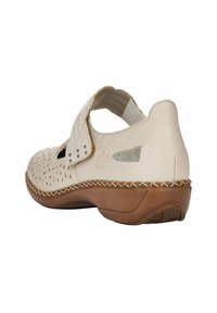 White leather shoe with cut-out design, adjustable strap, low heel, and braided detailing along the sole. Smooth texture, minimalist look.