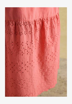 Koralen bombažni oblek s vezenimi cvetličnimi vzorci in izrezki v obliki očič vzdolž roba. Mehka tekstura z nabranim dizajnom.