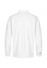 Camicia bianca a maniche lunghe con pince sulla schiena, colletto con bottoni e polsini con bottoni. Presenta sottili accenti del marchio nei colori rosso, bianco e blu.