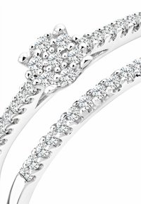 Anillo de cluster floral de diamantes en oro blanco. Presenta un cluster central de diamantes redondos y un shank dividido con diamantes más pequeños engastados en garra.