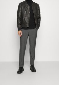 Schwarze Leder-Bomberjacke, passender schwarzer Rollkragenpullover, graue maßgeschneiderte Hose und schwarze Knöchelstiefel. Einfaches Design mit schlanker Erscheinung.