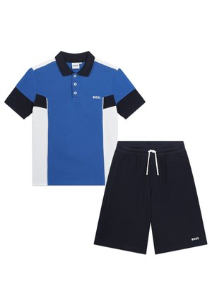 Blauw en witte poloshirt met een kraag, drie knopen en contrasterende mouwen. Gecombineerd met marineblauwe shorts met een elastische tailleband en een logo.