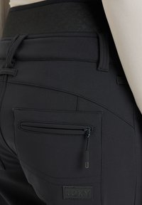 Zwarte sportbroek met een gladde textuur, een ritszak en het Roxy-logo. Beschikt over een hoge tailleband voor een snug fit.