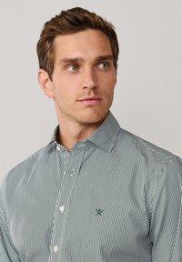 Gestreept shirt in groen en wit, met knoopsluiting op de kraag en geborduurd logo op de borst. Tailored fit met een soepele textuur.