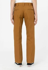 Braune Hose im geraden Schnitt, mit Gesäßtaschen mit Klappen, Gürtelschlaufen und einem glatten, strukturierten Stoff. Getragen mit schwarzen Schuhen.