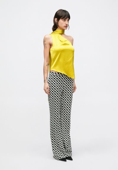 Žltý saténový top bez rukávov s preloženým výstrihom a asymetrickým lemom, kombinovaný s čiernobielymi širokými nohavicami s vysokým pásom a vzorom.