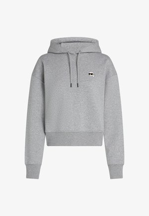 Gaiši pelēks saplacināts kapučs, izgatavots no mīksta auduma, ar auklu kapuci un nelielu grafisku logo krūšu rajonā. Ērta piegriezuma.