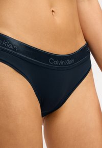 Granatowe bikini Calvin Klein wykonane z gładkiego materiału, z miękkim pasem w kontrastowym szarym kolorze z logo marki.