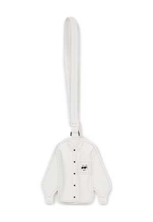 Biały skórzany brelok w kształcie koszuli z długim rękawem, z czarnymi guzikami i kieszonką zdobioną rysunkiem kota w stylu kreskówkowym. Gładka tekstura.