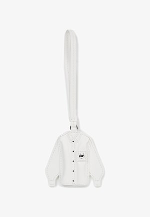 Biały skórzany brelok w kształcie koszuli z długim rękawem, z czarnymi guzikami i kieszonką zdobioną rysunkiem kota w stylu kreskówkowym. Gładka tekstura.