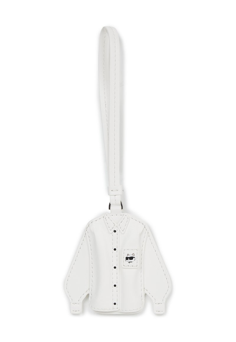 Biały skórzany brelok w kształcie koszuli z długim rękawem, z czarnymi guzikami i kieszonką zdobioną rysunkiem kota w stylu kreskówkowym. Gładka tekstura.