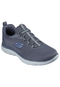 Zapatilla atlética gris con parte superior de malla, sistema de cordones en contraste y una suela ligera. Presenta un logo en el lateral y tela texturizada.