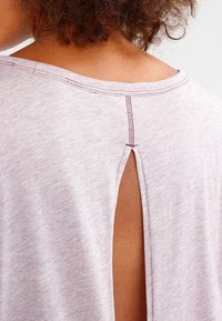 Ljuslila t-shirt med rund halsringning och en nyckelhålslörning bak. Mjuk, texturerad tyg med rosa sömnadsdetaljer.