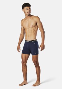 Navy cotton boxer briefs with a black waistband featuring "Smartwool" logo. Fitted design, smooth texture, and mid-thigh length.
