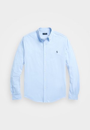 Jasnoniebieska, koszula na długi rękaw zapinana na guziki, z kołnierzykiem, białe guziki oraz haftowane logo Polo Ralph Lauren na lewej piersi.