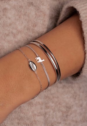 Sudraba rokassprādzes uz plaukstas ietver trīs gludas bangles un šarmu rokassprādzi ar kajakli un zirgastiņu siluetu.