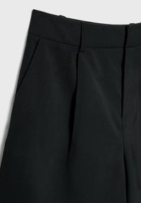 Pantalon noir taille haute avec passants de ceinture, plis à l'avant et poches latérales, présenté de la taille jusqu'à la moitié de la cuisse sur fond blanc.