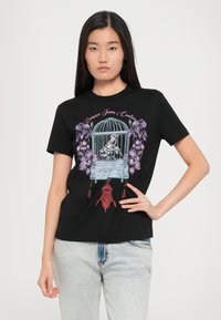 Black cotton t-shirt featuring a colorful graphic of a birdcage with a bird and orchids, embellished with detailed patterns and accents.