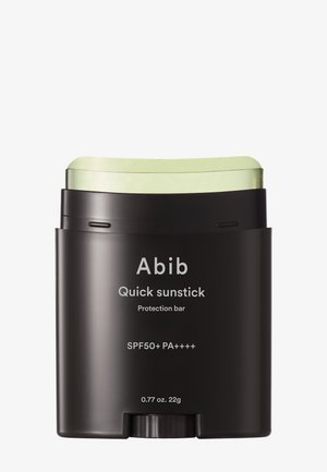 Conteneur noir rectangulaire avec un bâton vert, étiqueté "Abib Quick sunstick." Comprend SPF50+ PA++++, 0,77 oz (22g), design minimaliste.