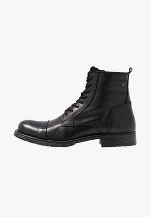 Bottine noire en cuir à lacets avec bout arrondi, détails de couture et petit talon empilé, vue du côté extérieur sur fond blanc.