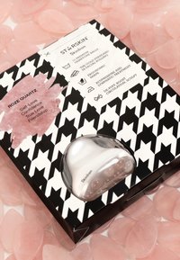 Emballage d'un produit de soin de la peau en quartz rose avec un motif pied-de-poule noir et blanc. Contient 10 billes en pierre ergonomiques pour le massage facial.
