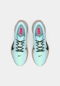 Ein Paar hellblaue Nike-Laufschuhe mit schwarzen Schnürsenkeln und Logos, mintgrüner Zungenstreifen und beigen Sohlen, von oben betrachtet.