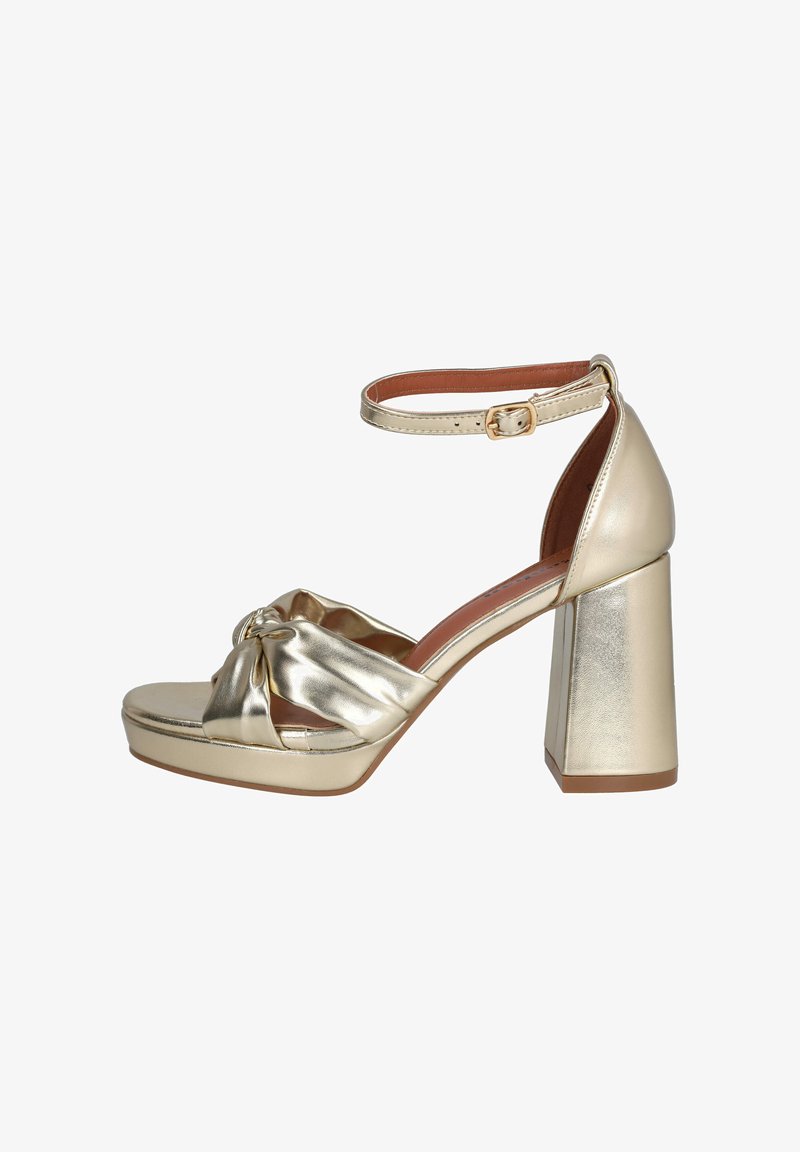 Sandalia de tacón alto metálica dorada con un tacón ancho de bloque, una correa frontal anudada y una correa en el tobillo con cierre de hebilla.