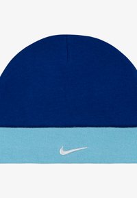Bonnet en tricot bleu et bleu clair avec un revers et un logo Nike blanc brodé à l'avant. Texture douce avec un design sans couture.