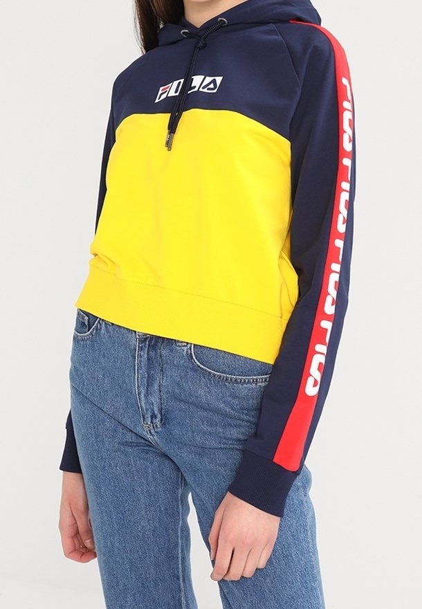 Felpa con cappuccio a blocchi di colore con corpo giallo e cappuccio blu navy, con un accento rosso sulla manica e logo bianco. Materiale in misto cotone, design corto.