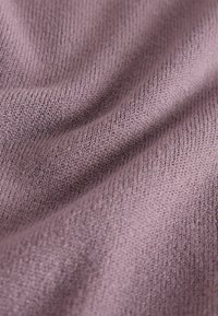 Tela tejida de color lavanda suave con patrones de puntadas visibles y pliegues suaves que crean textura y profundidad.
