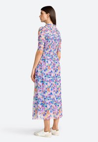 Blumenkleid aus leichtem, durchsichtigem Stoff mit gerafftem Oberteil und kurzen Ärmeln, das eine Mischung aus lila, rosa und blauen Blumen zeigt.