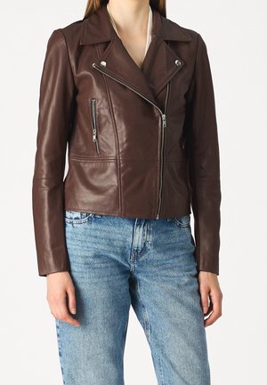 Braune Leder-Bikerjacke mit asymmetrischem Reißverschluss und Reißverschlusstasche auf der Brust, getragen mit hellblauen Denim-Jeans.