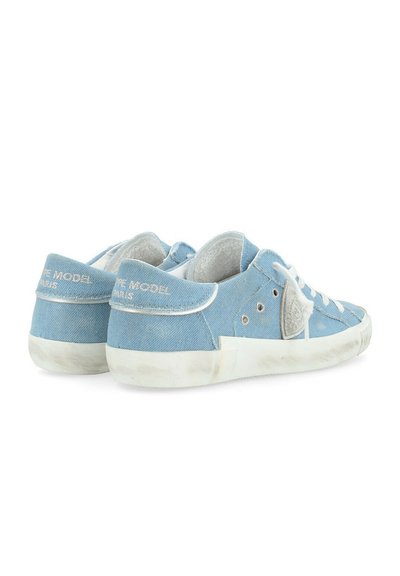Sneakers bassi in denim blu con suole in gomma bianca, lati perforati e logo ricamato sul tallone. I lacci sono bianchi e il tessuto è morbido.